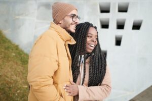 A joyful couple embracing outdoors, dressed warmly for winter, showcasing affection and style.