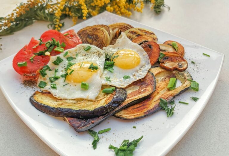 a white plate topped with fried eggs and vegetables. Imagem ilustrativa para Batata com Cebola e Ovos na Frigideira.