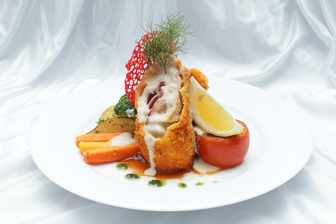 French traditional cuisine chicken cordon bleu with cheese, ham, potatoes, and vegetable salad on the plate.. Imagem ilustrativa para Caçarola de Frango Cordon Bleu: Uma Receita Fácil e Irresistível.