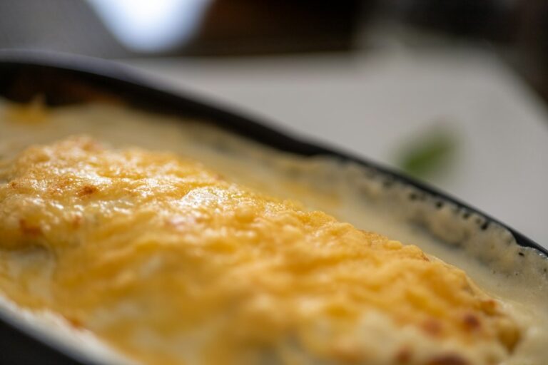 a casserole dish with cheese on top of it. Imagem ilustrativa para Enchiladas de Frango com Cream Cheese: Uma Receita Irresistível.