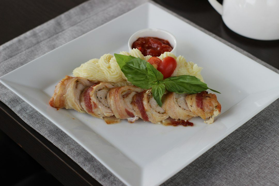 Bacon-wrapped meatloaf with mashed potatoes and sauce. Imagem ilustrativa para Lombo de Porco Recheado com Queijo e Bacon.