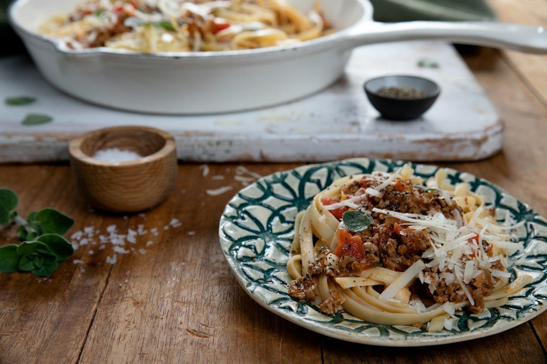 a plate of pasta with meat sauce and parmesan cheese. Imagem ilustrativa para Macarrão Cremoso com Calabresa em Uma Panela.