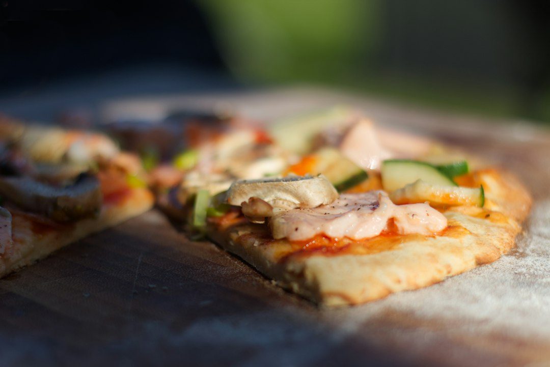 pizza with green vegetable on brown wooden table. Imagem ilustrativa para Receita Prática de Pizza Caseira com Legumes.