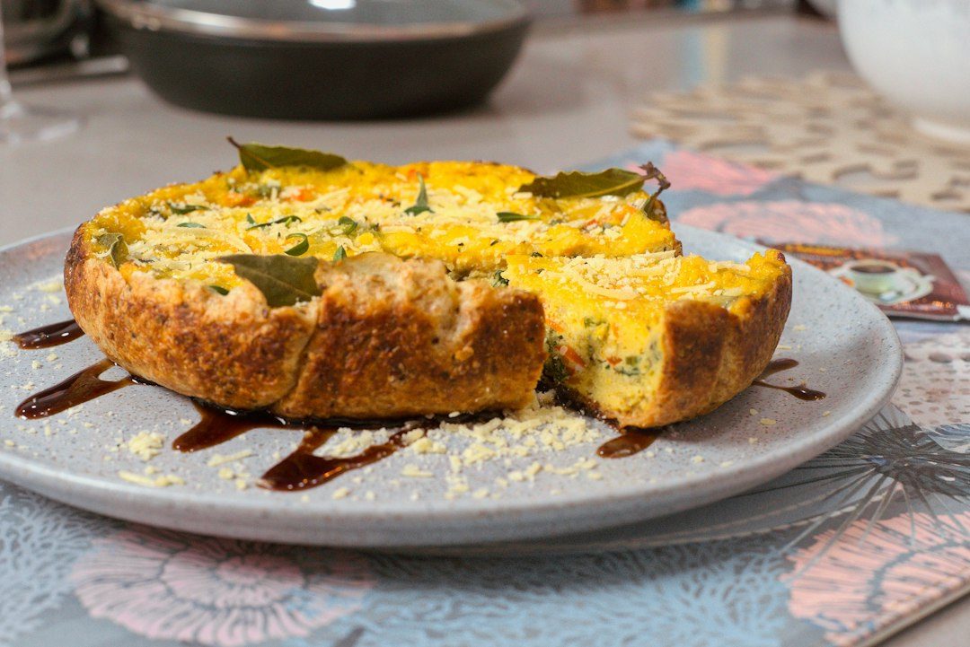 a quiche with a piece cut out of it on a plate. Imagem ilustrativa para Torta de Pão Fácil e Deliciosa: Receita Rápida para Surpreender!.
